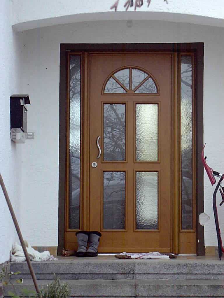 Haustüre aus hellem Rotholz und zwei festen Seitenteilen